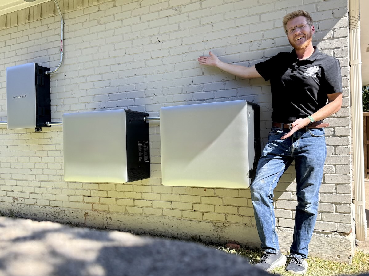 Drew beside a wall-mounted solar battery installation